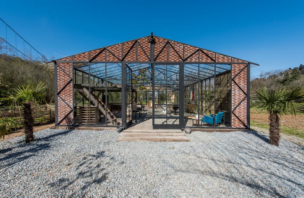 The entrance façade of Anadolu Hisarı Garden, with a brick pediment, black steel framing and glass doors.